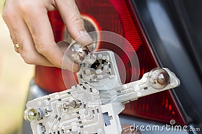 The mechanic`s hand inserts the bulb into the frame lamp of the car. Stock Photo