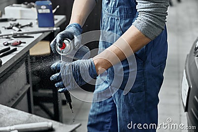 Mechanic spraying substance to remove rust from spark plug Stock Photo