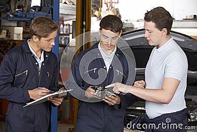 Mechanic Teaching Trainees In Garage Workshop Stock Photo