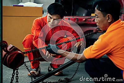 Mechanic testing strength and reliability of chain hoist for car towing. Oxus Stock Photo