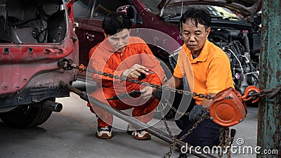 Mechanic testing strength and reliability of chain hoist for car towing. Oxus Stock Photo