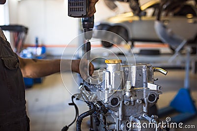 Mechanic with a tool in his hands repairing the motor of the machine. Stock Photo