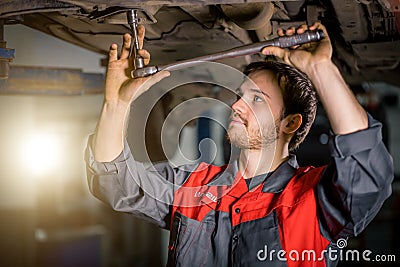 Mechanic under car in garage examing tire and technical condition Editorial Stock Photo