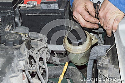 The mechanic unscrews the nut in the area of the front bumper of the car with a wrench Stock Photo