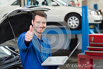 Mechanic using his laptop showing thumbs up Stock Photo