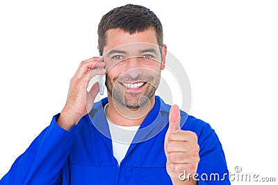 Mechanic using mobile phone while gesturing thumbs up Stock Photo