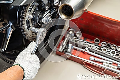 Mechanic using a wrench and socket on motorcycle sprocket .maintenance and repair concept in motorcycle garage .selective focus Stock Photo