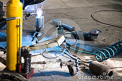 Mechanic welds pipe on corrugation muffler Stock Photo