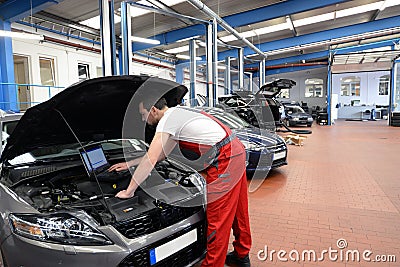 mechanic in a workshop checks and checks the electronics of the car - software update with a modern computer Stock Photo