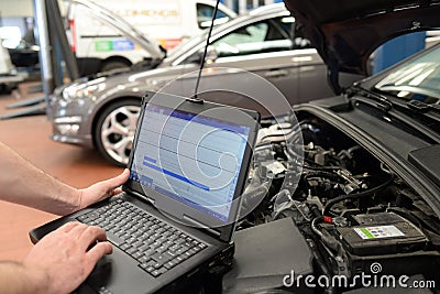 mechanic in a workshop checks and checks the electronics of the car - software update with a modern computer Stock Photo