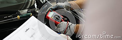 Mechanical service using multimeter to check voltage level in car battery and auto documentation diagram Stock Photo