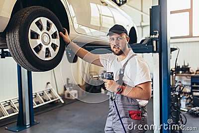 Mechanician changing car wheel in auto repair service Stock Photo