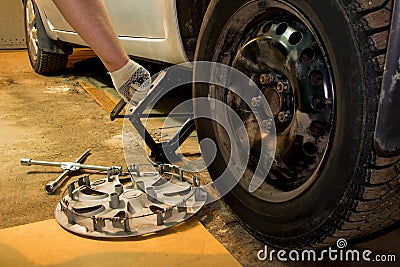 Mechanician changing car wheel in garage. Man exchanging tire. Tire service. Stock Photo