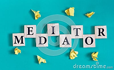 MEDIATOR - word on wooden cubes on a green background with crumpled yellow papers Stock Photo