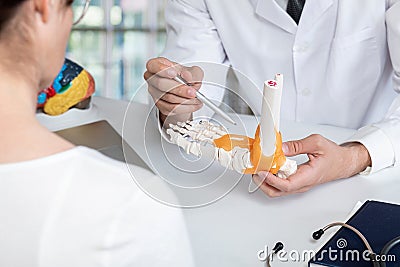 Medic shows ankle diseases to patient Stock Photo