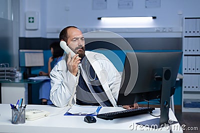 Medic using landline phone for remote communication overtime Stock Photo