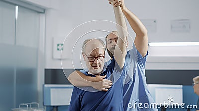 Medical assistant raising arms of elder person to stretch muscles Stock Photo