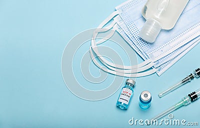 Medical bottle, hand sanitizer, vials, syringes and face mask on blue background with copy space. Vaccination session and immunity Stock Photo