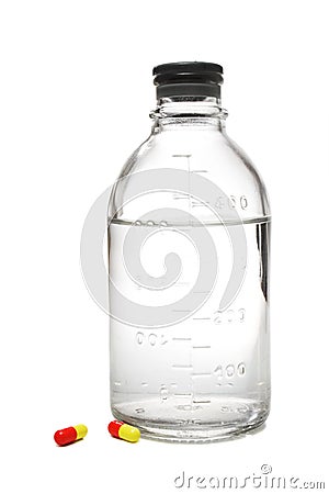 Medical bottle with saline and pills beside it Stock Photo