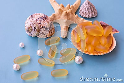 Medical capsules of omega 3 natural fish oil on a half of seashell on blue background Stock Photo