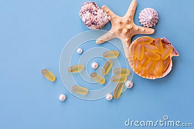 Medical capsules of omega 3 natural fish oil on a half of seashell on blue background. Stock Photo