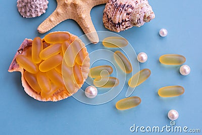 Medical capsules of omega 3 natural fish oil on a half of seashell on blue background Stock Photo