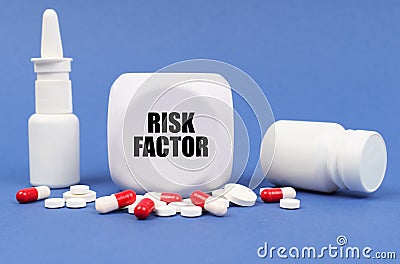 On the blue surface of the pill, capsule, spray, jar and cube with the inscription - RISK FACTOR Stock Photo