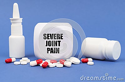 On the blue surface of the pill, capsule, spray, jar and cube with the inscription - severe joint pain Stock Photo