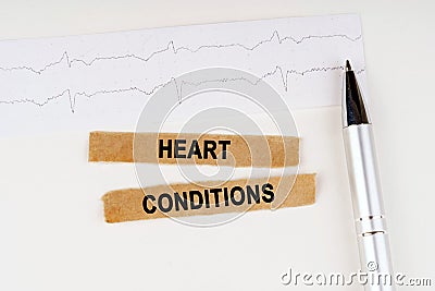 On the cardiogram lies a pen and torn paper with the text - HEART CONDITIONS Stock Photo