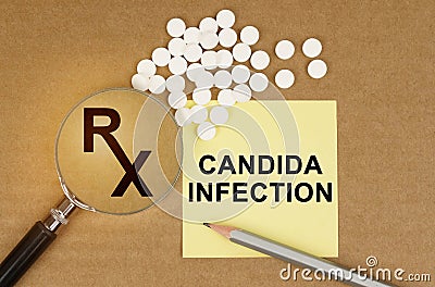 On the table are pills, a magnifying glass, pencils and a sticker with the inscription - Candida Infection Stock Photo