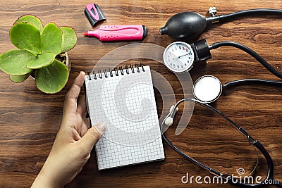 medical concept text writing on white notebook and black stethoscope, sphygmomanometer on wood table. Stock Photo