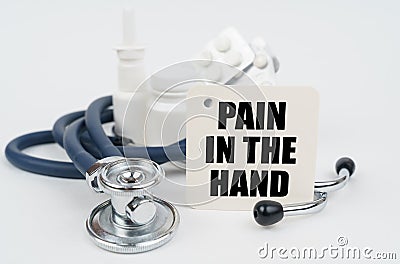 On a white surface, medicines, a stethoscope and writing paper with the text - pain in the hand Stock Photo