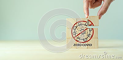 Medical and Covid-19 zero covid concept. Coronavirus virus cell symbolic. Hand puts the wooden cubes with ZERO COVID icon on grey Stock Photo