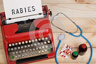 medical diagnosis - doctor workplace with blue stethoscope, pills, red typewriter with text Rabies Stock Photo