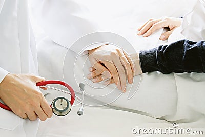 Medical doctor holding patient`s hands and comforting her with care. Stock Photo