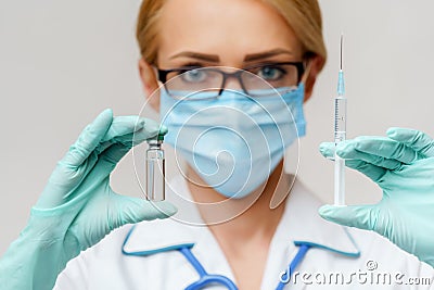 Medical doctor nurse woman wearing protective mask and gloves - holding bottle of vaccine medicine and syringe Stock Photo