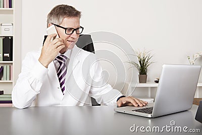 Medical Doctor Using Mobile Phone and Laptop Stock Photo