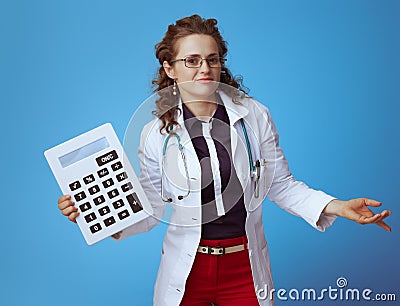 Medical doctor woman with big white calculator shrug on blue Stock Photo