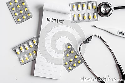 Medical equipment with stethoscope, list and pills in doctor`s office on white desk background top view mock-up Stock Photo