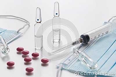 Medical face masks, pink pills, ampullas and expendable syringe for vaccination. Coronavirus vaccination concept. COVID-19 Stock Photo