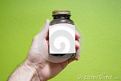 A medical glass bottle of brown color with a white label for your text and a bronze metal cap in a male hand Stock Photo