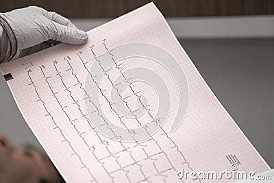 Electrocardiogram, ecg in hand, palm of a doctor. Clinic cardiology heart rhythm and pulse test closeup. Cardiogram printout. Stock Photo