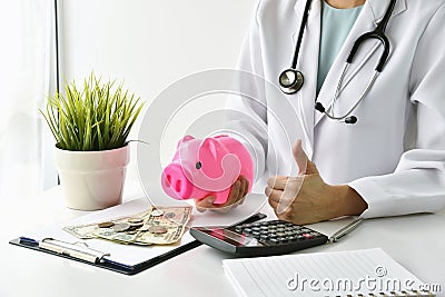 Medical and health insurance concept, Doctor holding piggy bank and money in hospital background. Stock Photo