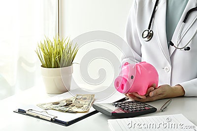 Medical and health insurance concept, Doctor holding piggy bank and money in hospital background. Stock Photo