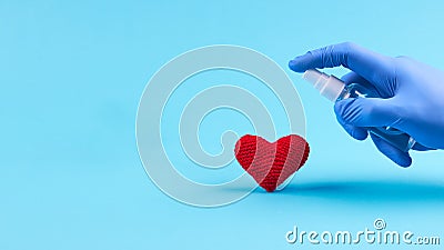 Medical heart treatment. person with blue latex gloves use sanitizer for heart symbol over blue background. copy space Stock Photo