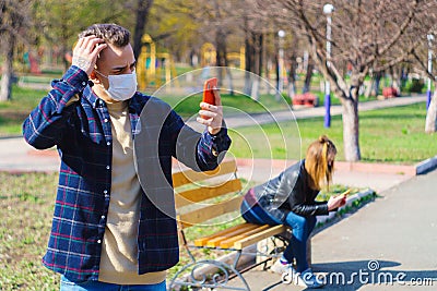 Medical mask as protection against coronavirus. a guy and a girl are sitting on a bench at a distance Stock Photo