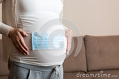 Medical mask on the belly of a pregnant girl. hild protection. Concept of coronavirus, covid-19, quarantine Stock Photo