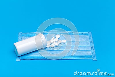 Medical mask with a bottle of a medicinal product with a scattered pile of pills. Stock Photo