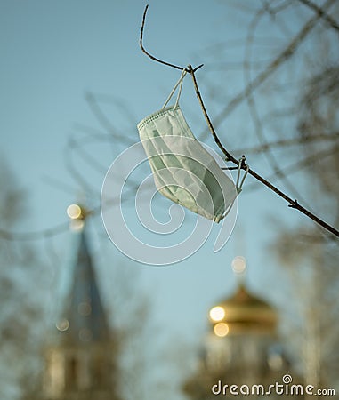 Medical mask hanging on a branch against the background of the Orthodox Church Stock Photo