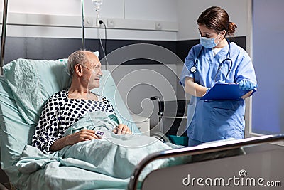 Medical nurse in scrubs with chirurgical mask taking notest on cliboard Stock Photo